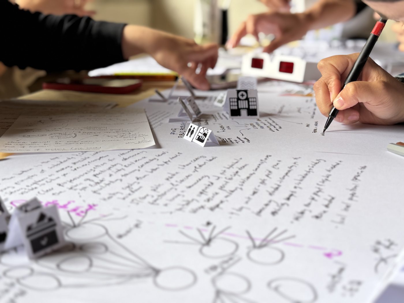 Workshop participants working collaboratively on paper diagrams and physical models